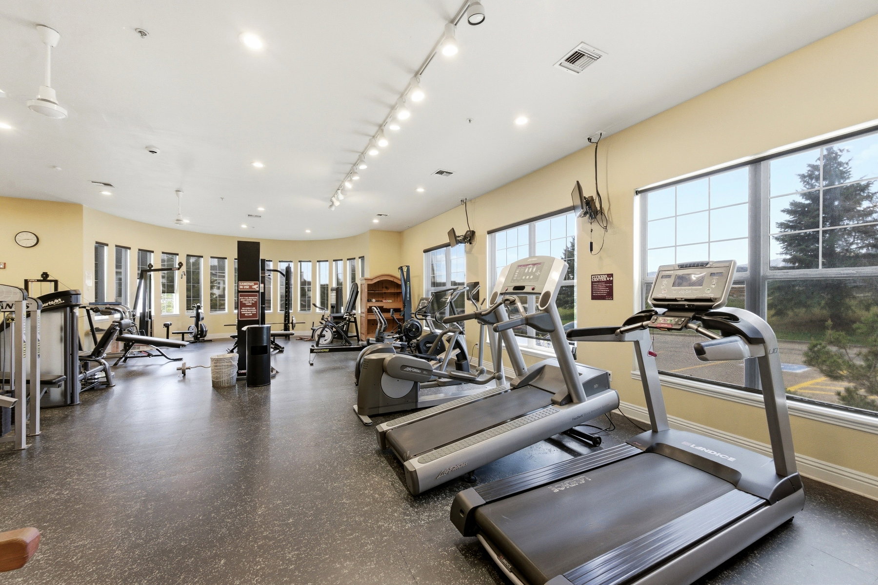 Fitness center featuring multiple treadmills, exercise equipment, expansive windows, recessed lighting, and resilient rubber flooring