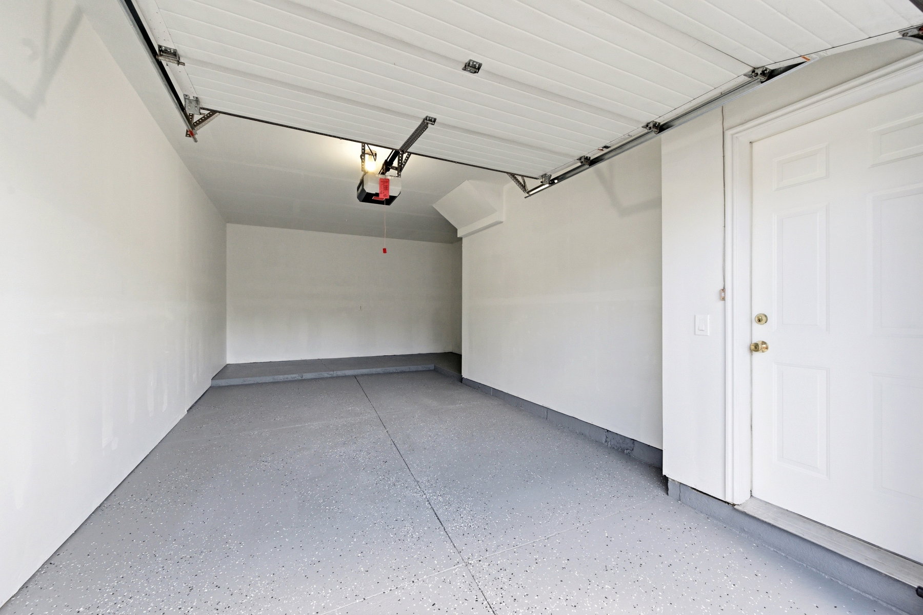 Spacious garage featuring a durable epoxy-coated floor, painted walls, and an automatic garage door opener