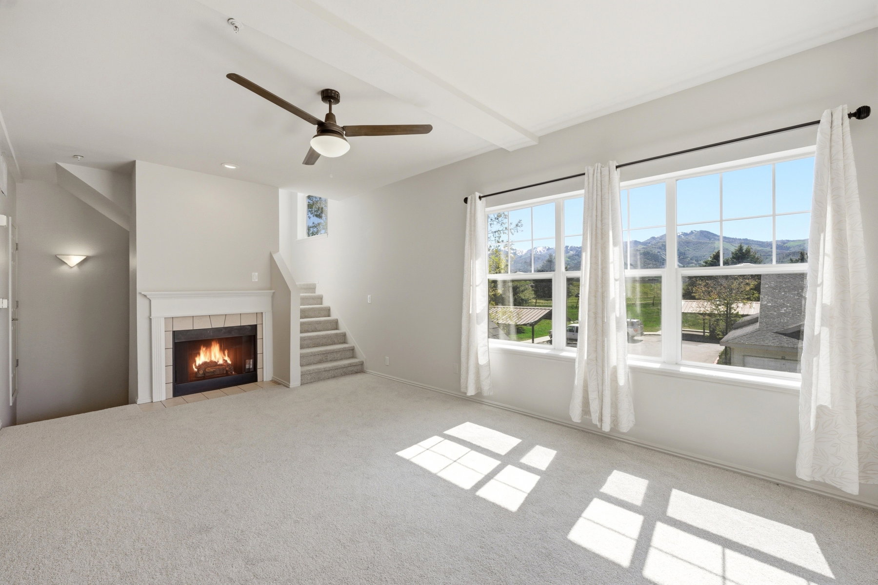Carpeted living area featuring a fireplace with tile surround, white mantel, and hearth