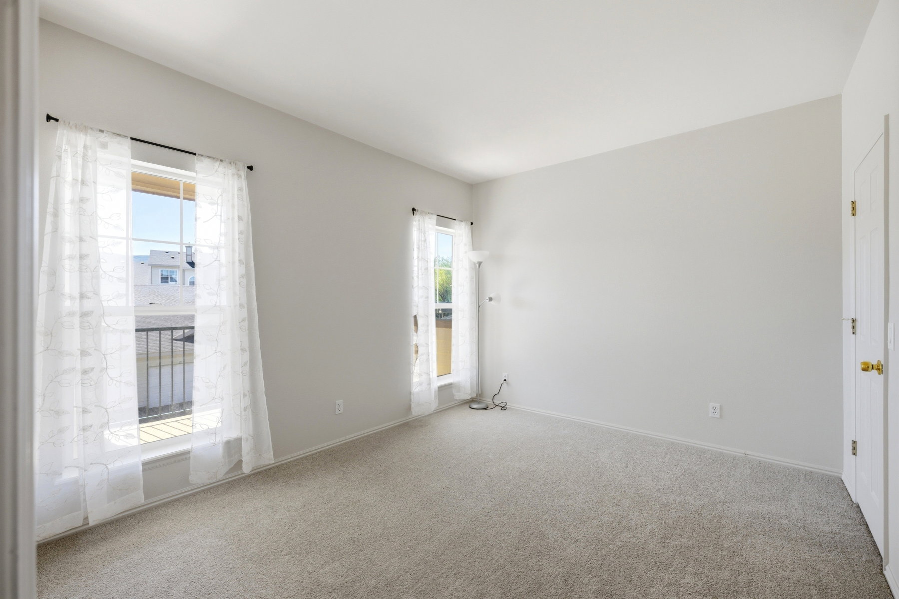 Bright room with two large windows, light gray walls, and light-colored carpeting