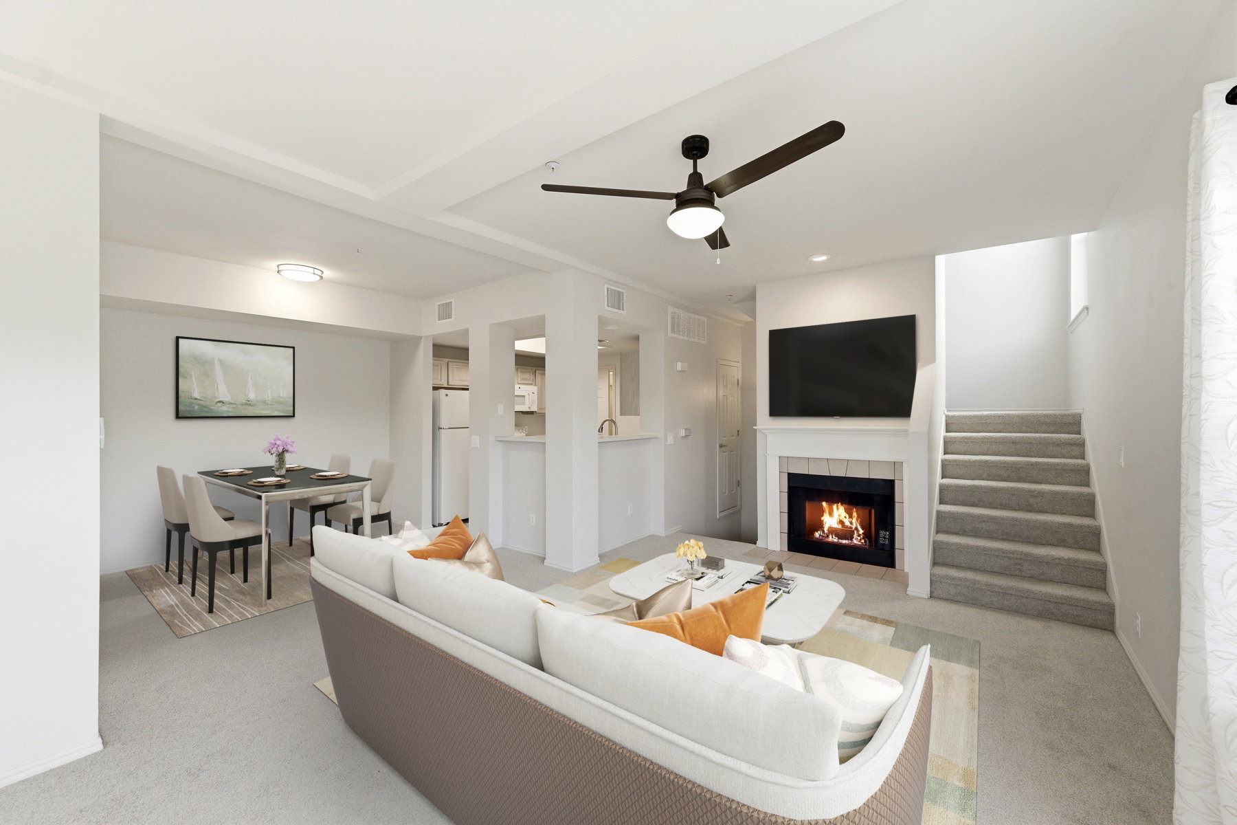 Spacious living area featuring carpet flooring, a ceiling fan, and a fireplace with a white mantel