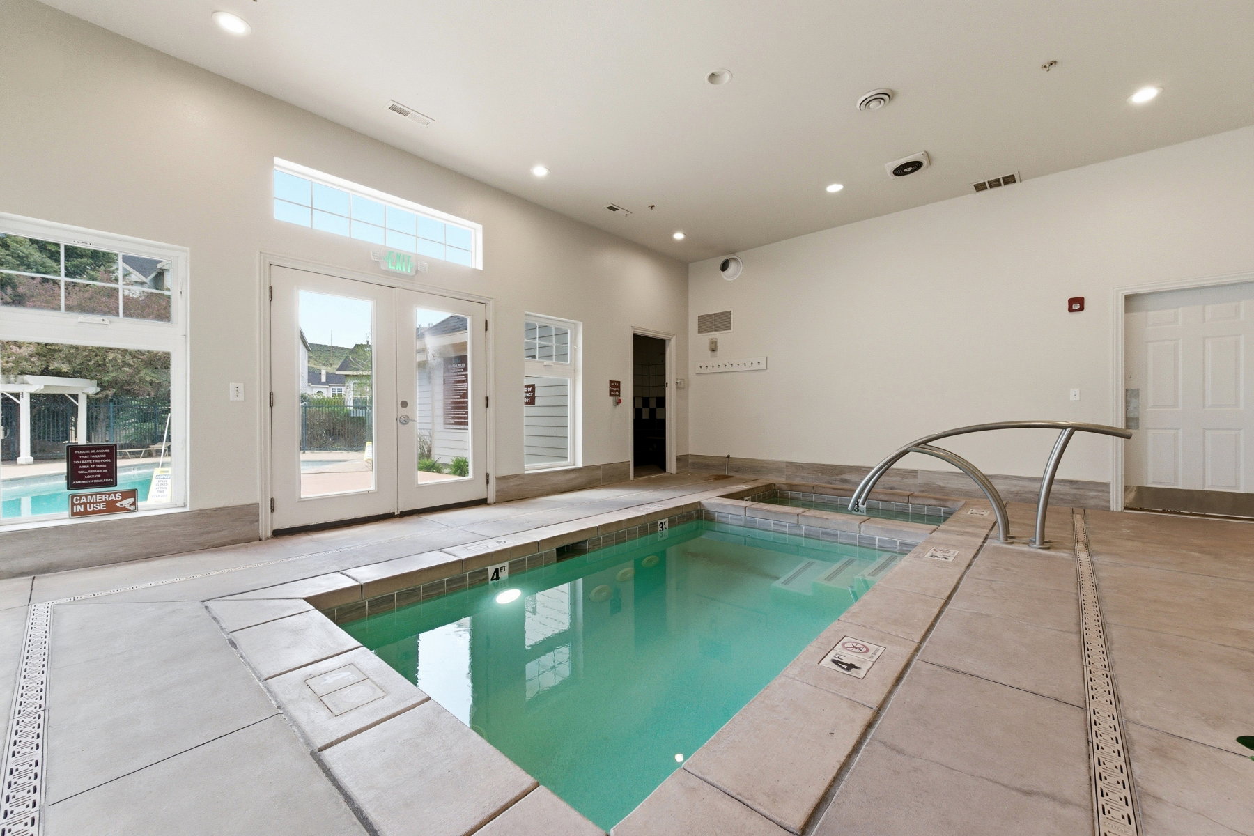 Indoor aquatic area featuring a large spa with an arched handrail and a smaller soaking tub
