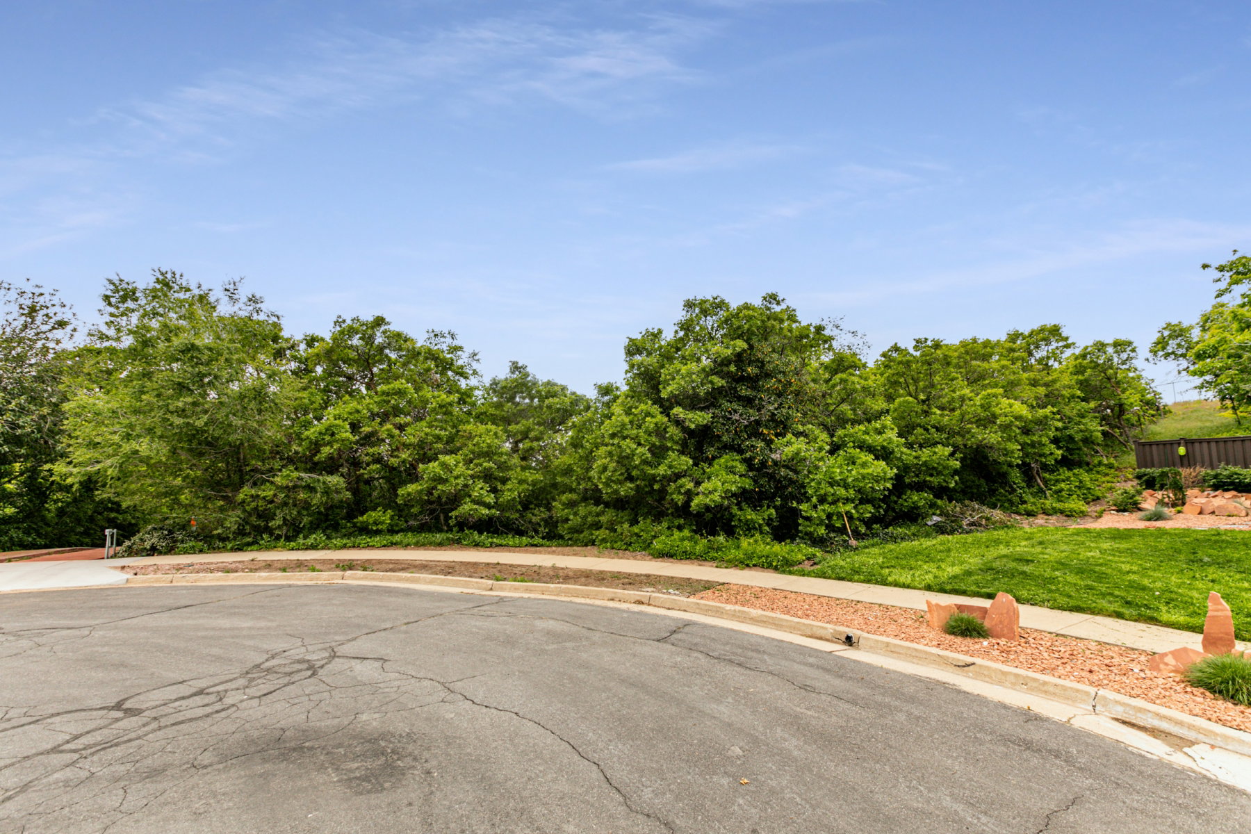 Lush green landscaping with mature trees, manicured lawn, and decorative rock features