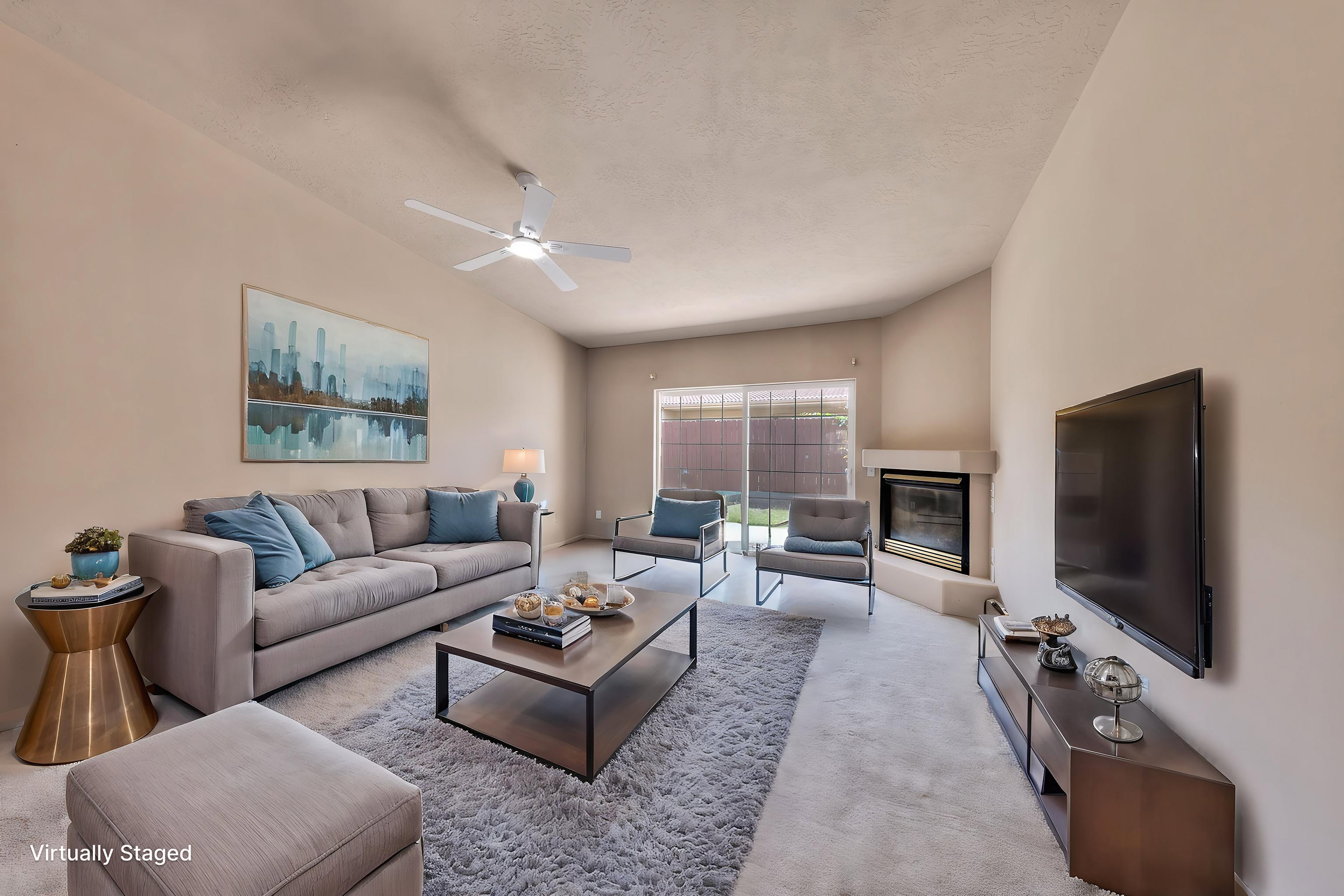 Living area featuring vaulted ceilings, a ceiling fan, plush carpet flooring, a corner fireplace, and sliding glass doors