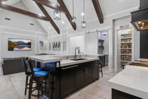 Open-concept kitchen featuring an oversized island with countertop seating, dark wood cabinetry, and light-toned countertops
