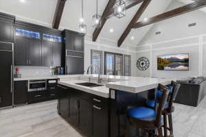 Kitchen featuring dark cabinetry, a large center island with a white countertop, stainless steel appliances, and a herringbone-patterned tile backsplash