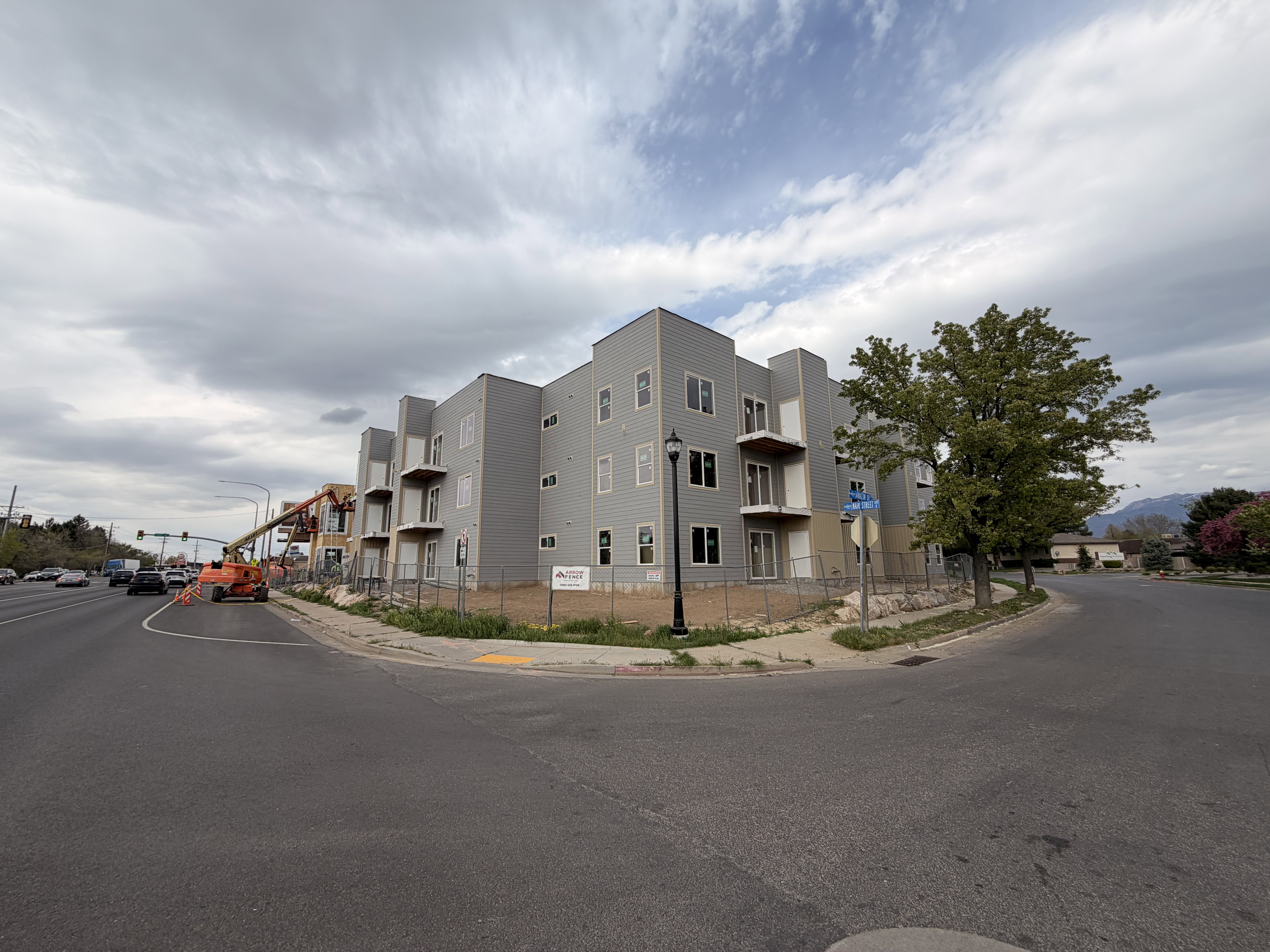 New construction multi-story building featuring light gray siding and multiple balconies with white railings