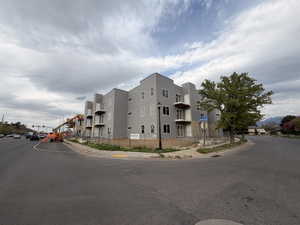 New construction multi-story building featuring light gray siding and multiple balconies with white railings