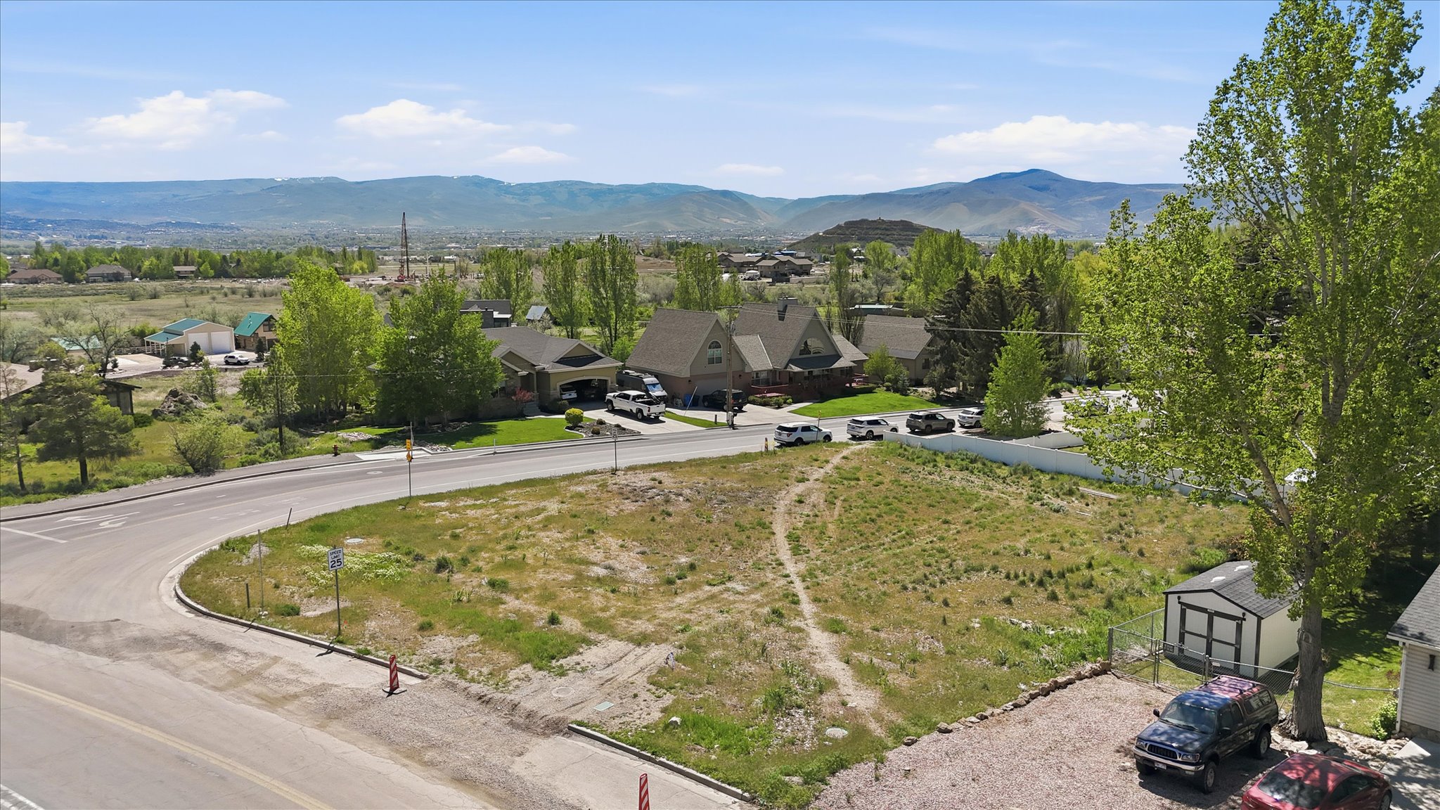 Elevated parcel featuring natural ground cover, distant mountain ranges, and a paved road frontage