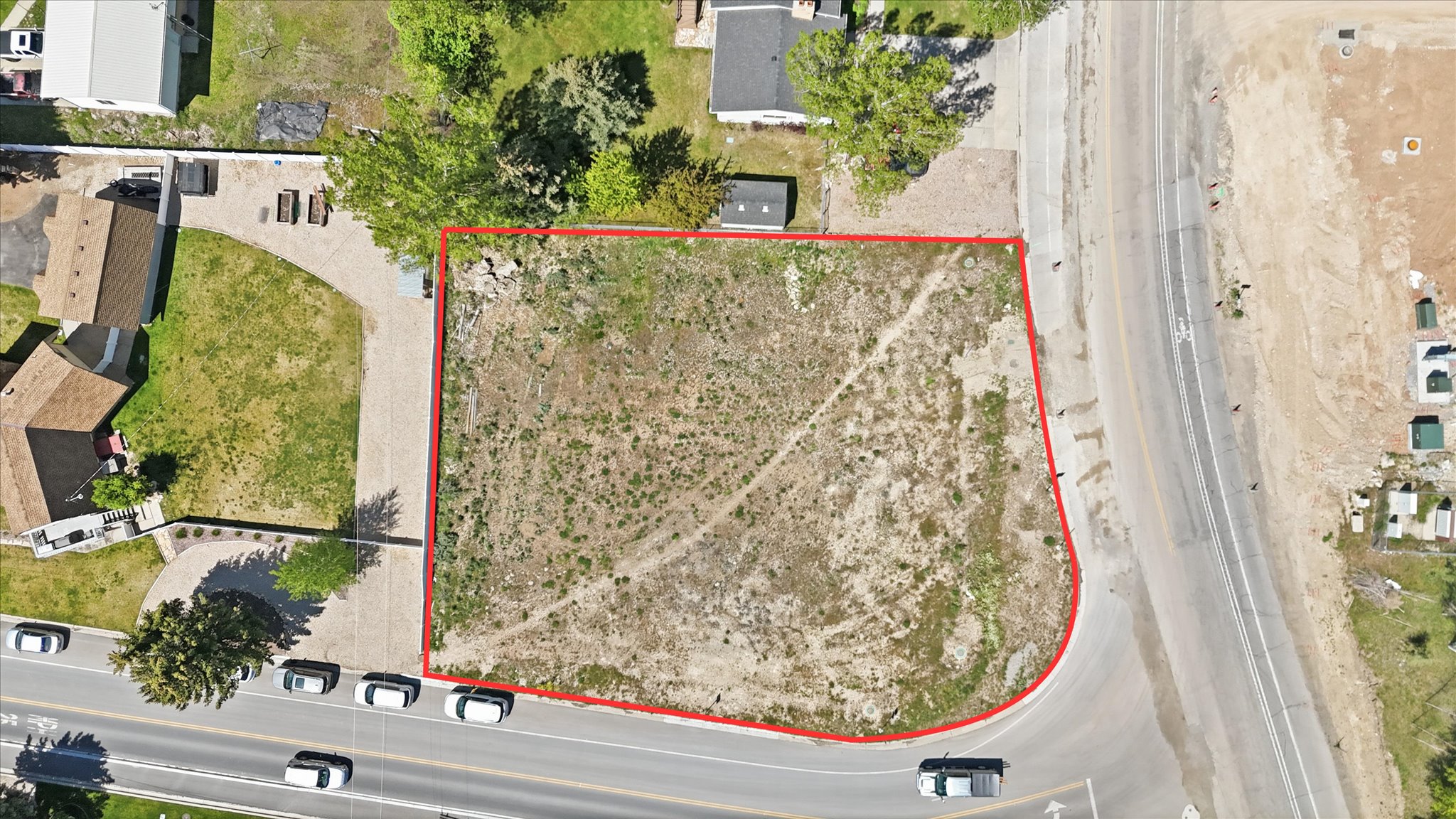 Expansive vacant lot with a perimeter outlined in red, featuring direct access to a paved road