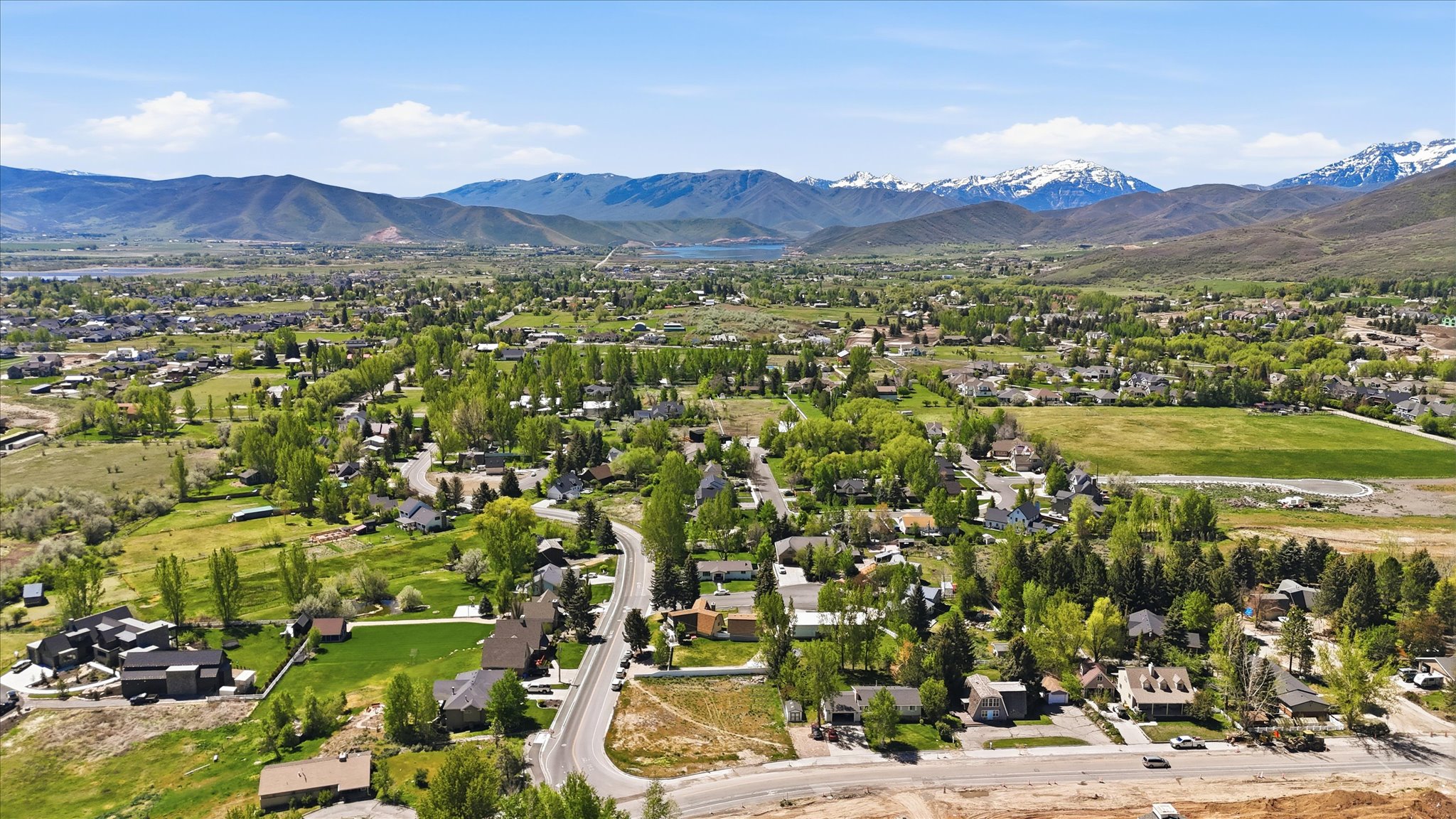 Expansive mountain valley setting featuring residential properties, verdant trees, and paved roadways
