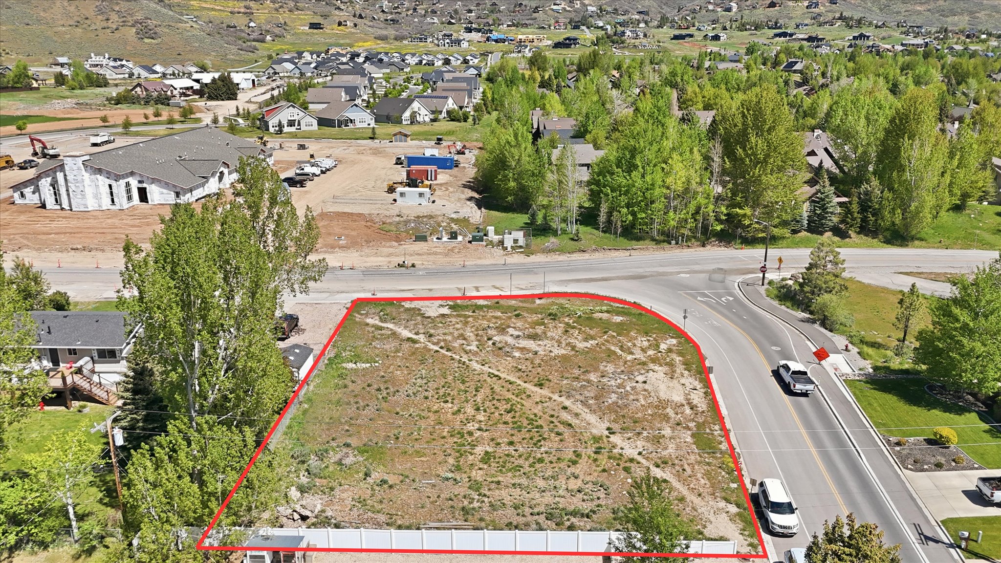 Expansive corner lot with paved road frontage, partially fenced perimeter, and established trees