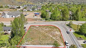Expansive corner lot with paved road frontage, partially fenced perimeter, and established trees