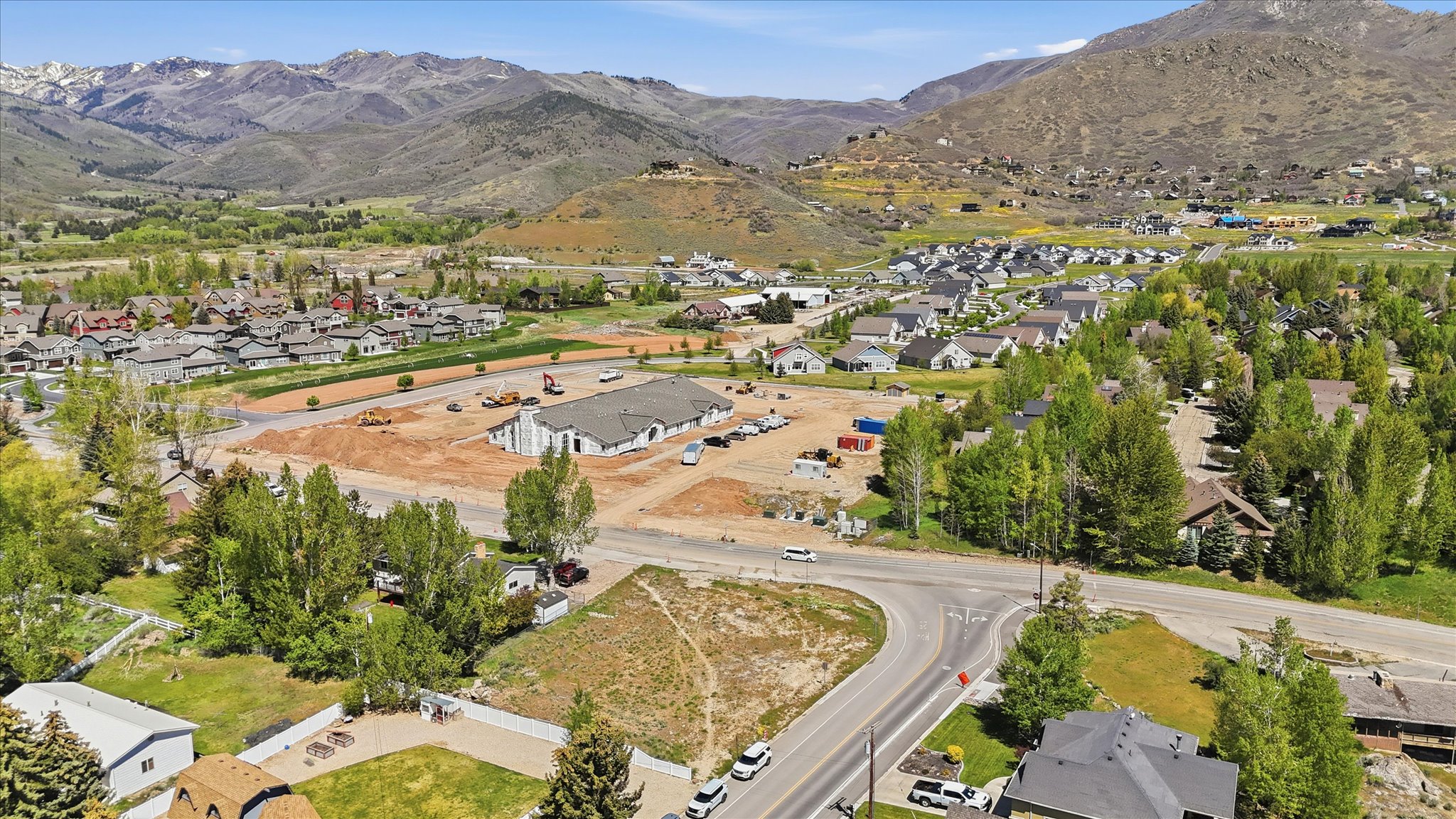 Expansive development site featuring active construction, surrounding residential properties, and paved roadways