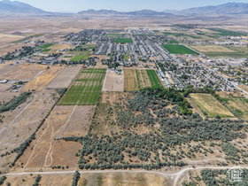 Expansive aerial perspective showcasing a rural landscape with agricultural fields, scattered residential development, and distant mountain ranges under a clear sky