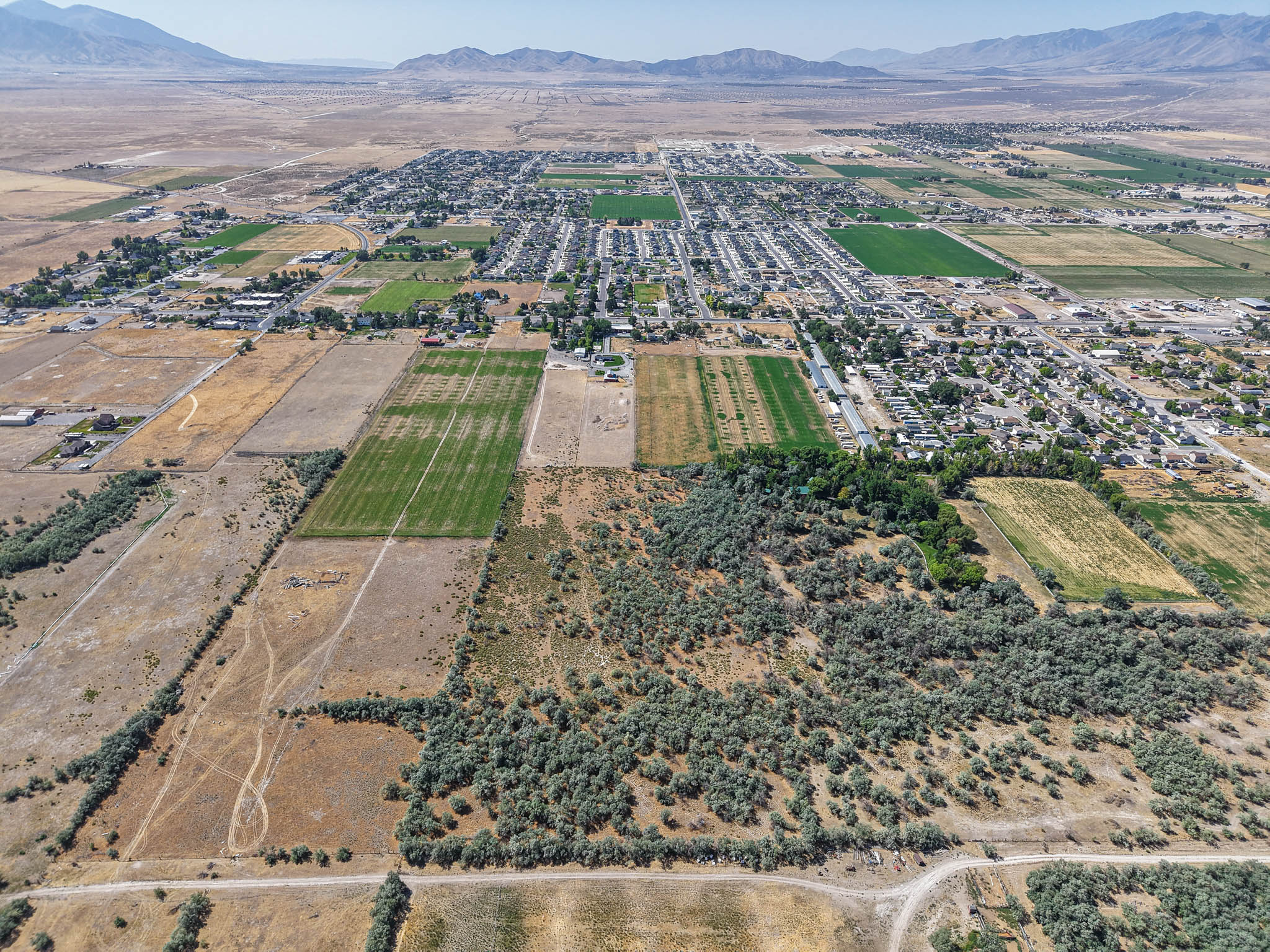Expansive aerial view showcasing a landscape characterized by open fields, cultivated land, and natural vegetation