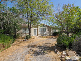 Single-story residence featuring a gravel driveway and surrounding mature trees