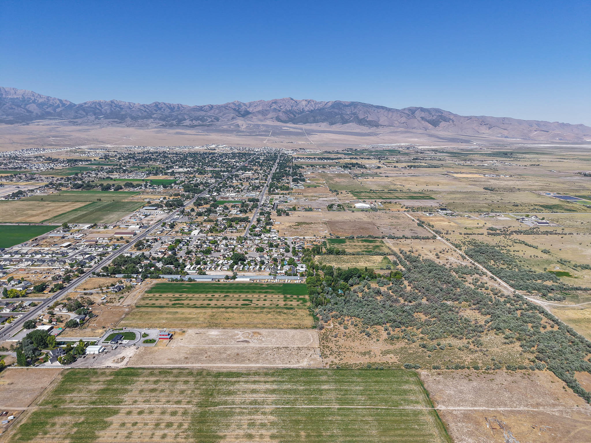 Expansive aerial landscape encompassing a residential community, agricultural fields, and distant mountain ranges