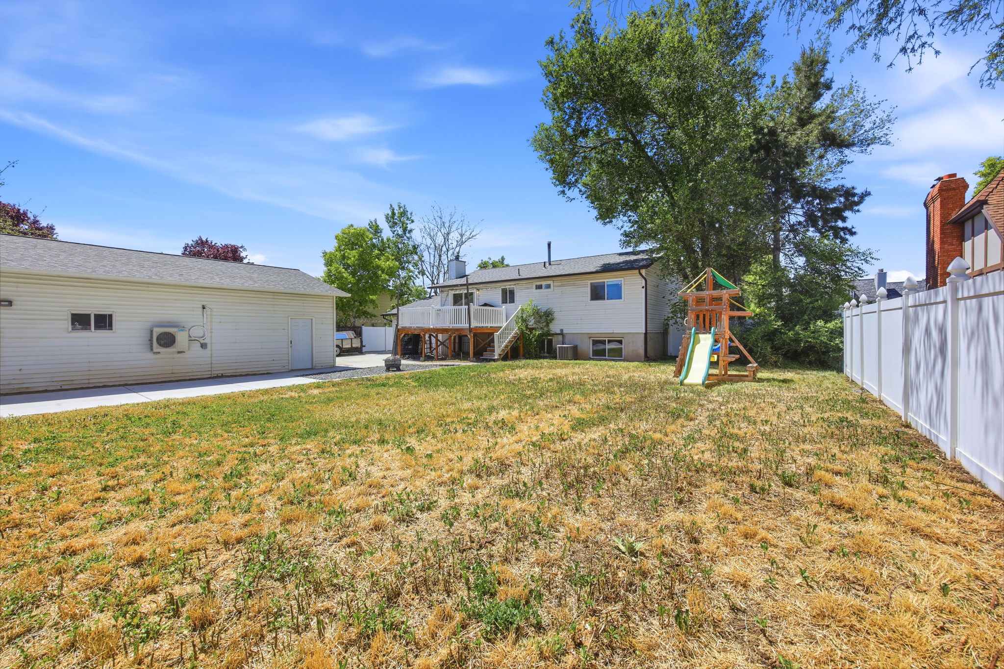 Spacious backyard featuring a white privacy fence and mature trees
