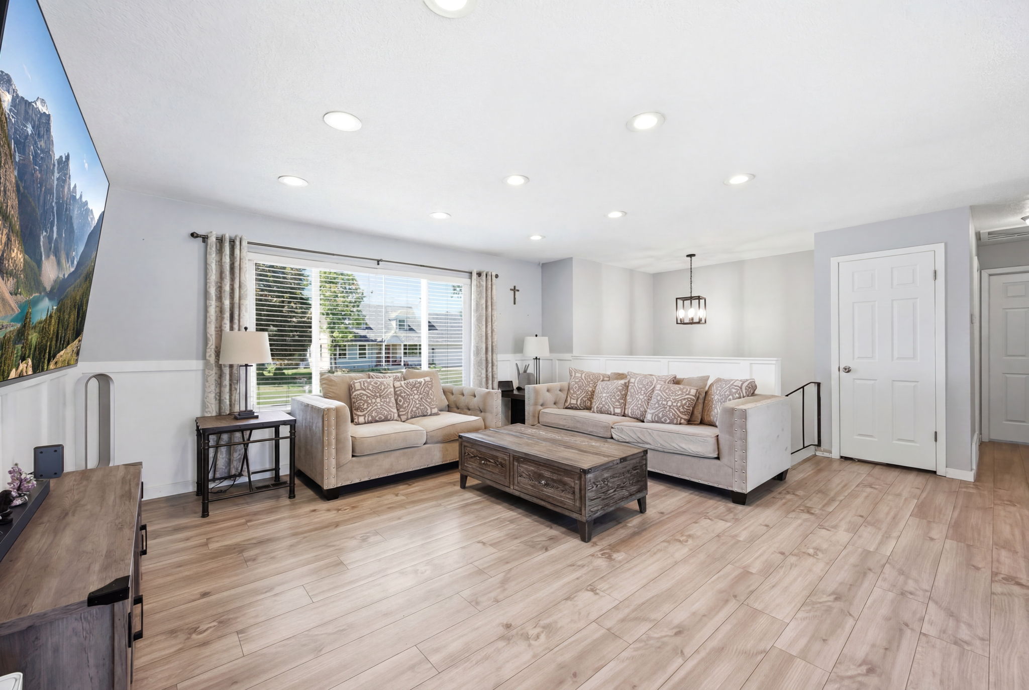 Spacious living area featuring wood-finish flooring, recessed lighting, and wainscoting