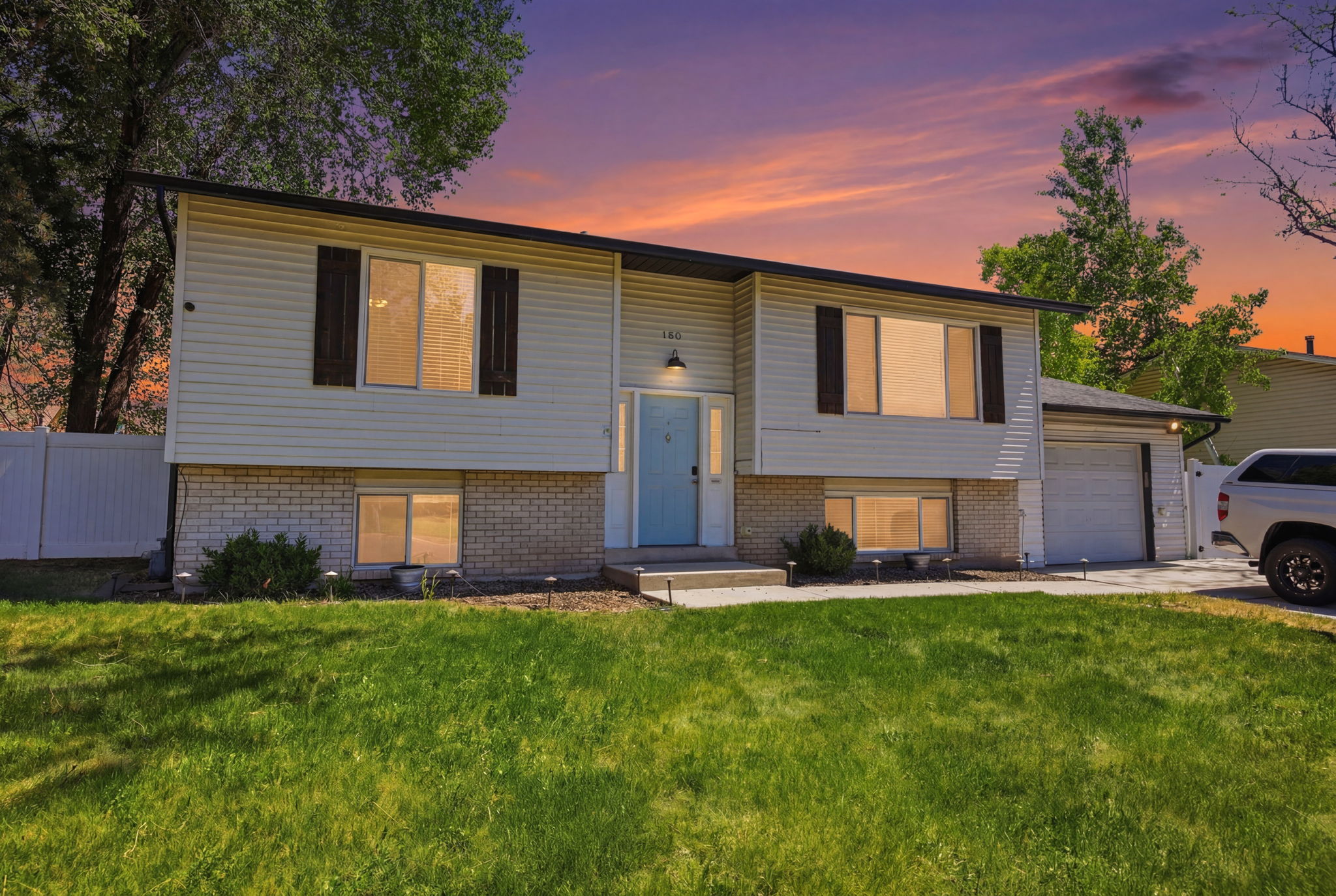 Split-level residence featuring light-colored siding and a brick base
