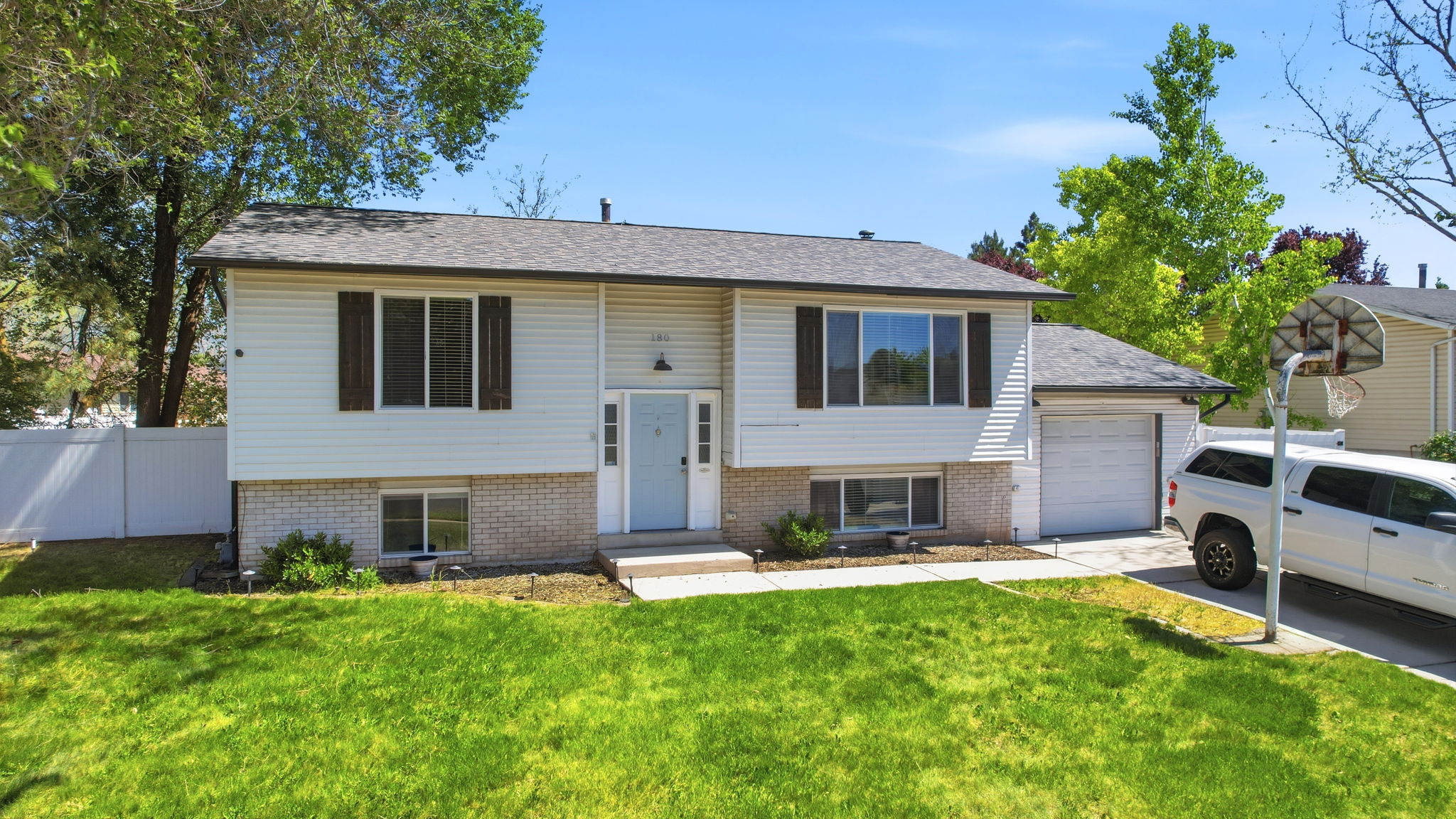 Split-level residence featuring white siding and a brick-look foundation