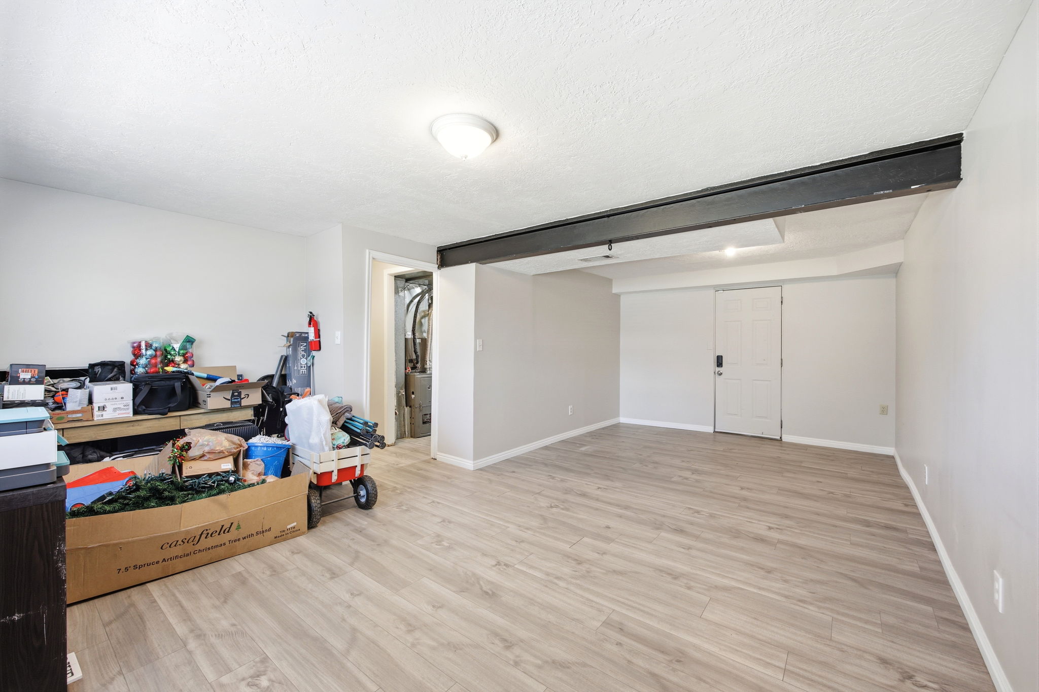 Spacious room featuring wood-finish flooring, light gray wall paint, white trim, and a white paneled door
