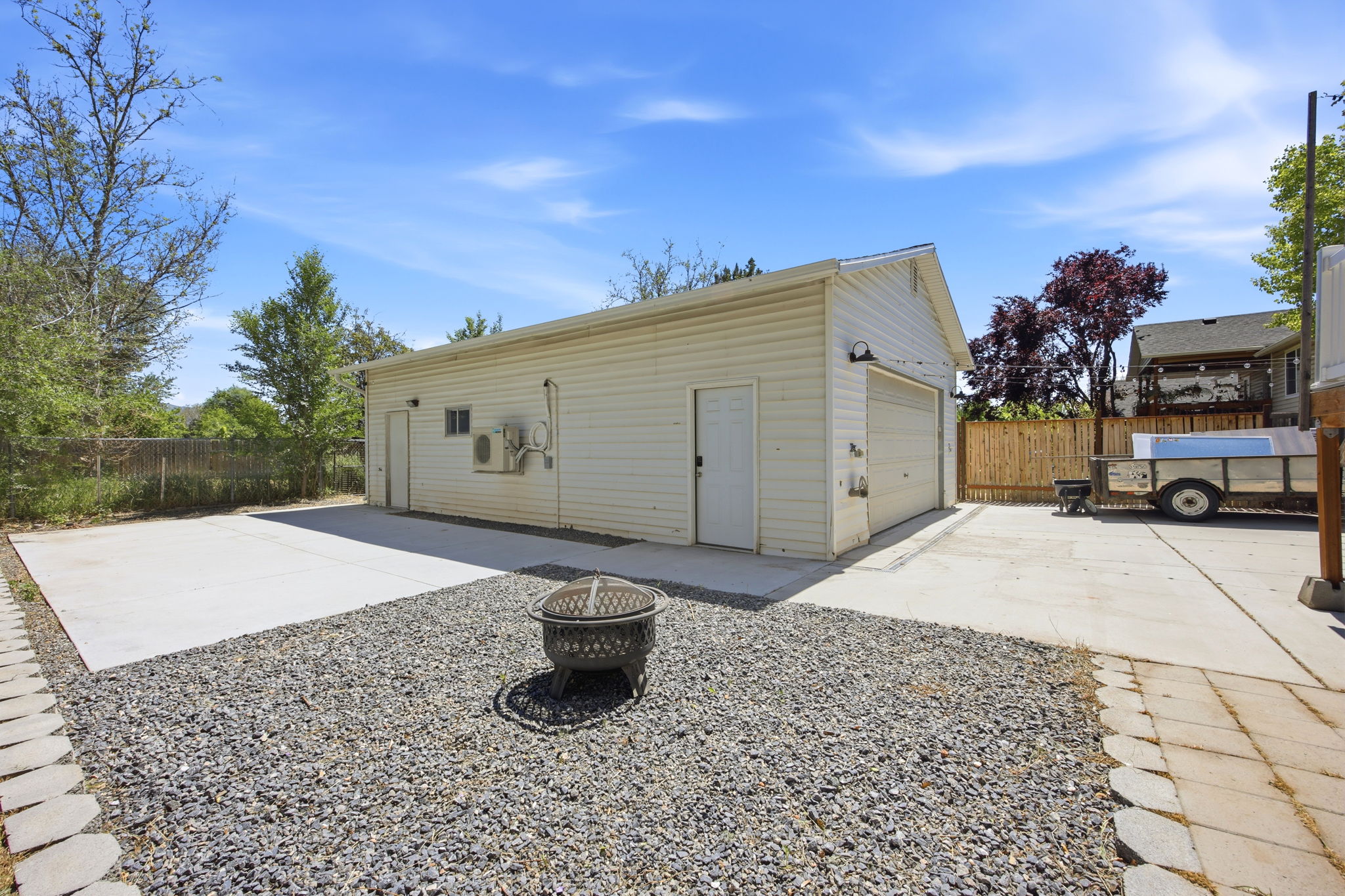 Detached two-car garage with white siding and multiple access doors