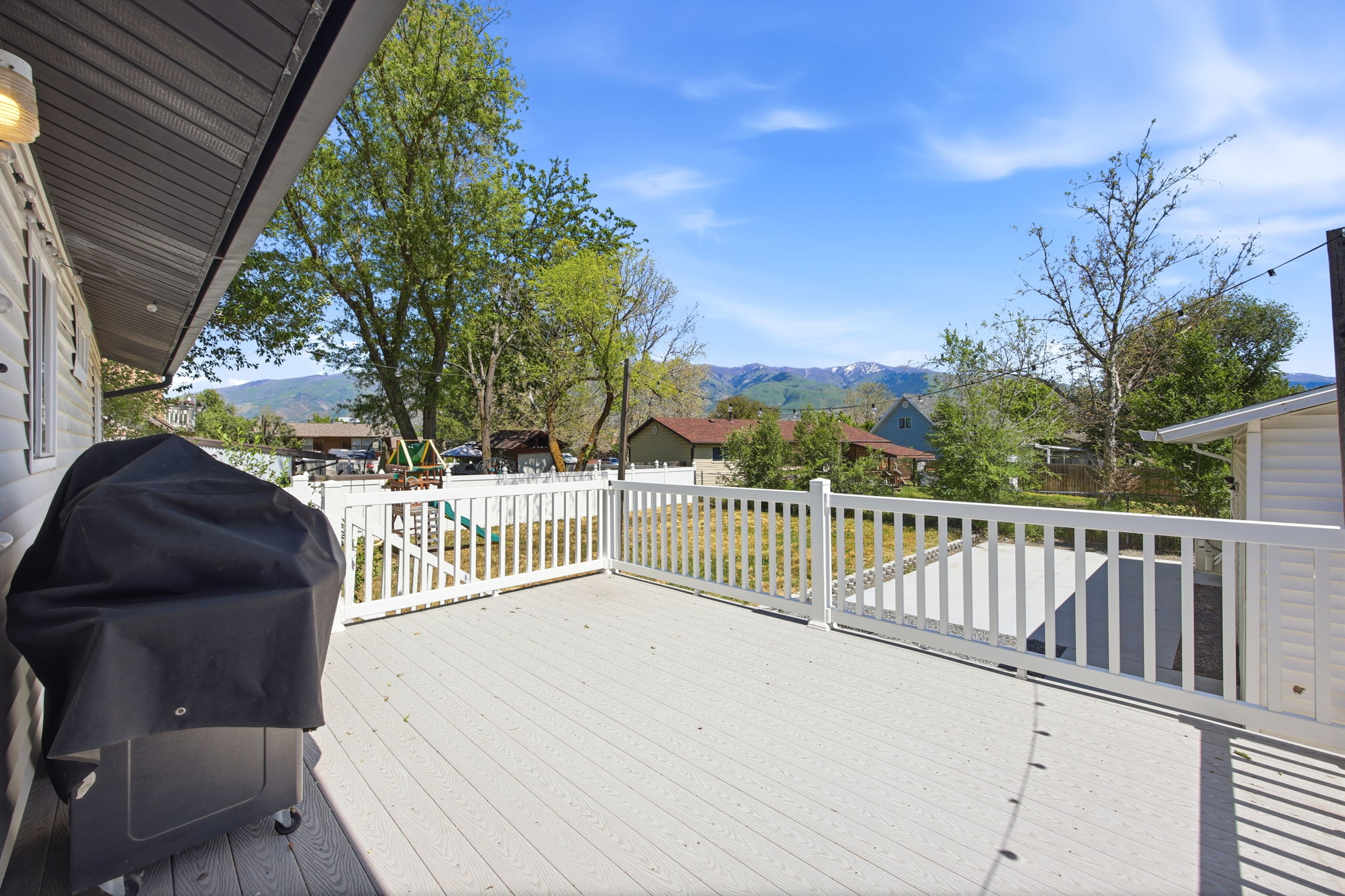 Spacious outdoor deck with a white railing, composite decking, and a backdrop of distant mountains