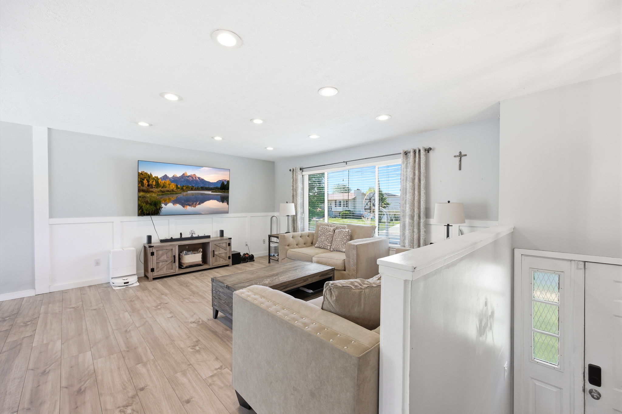 Open living area with recessed lighting, light wood-finish flooring, and wainscoting