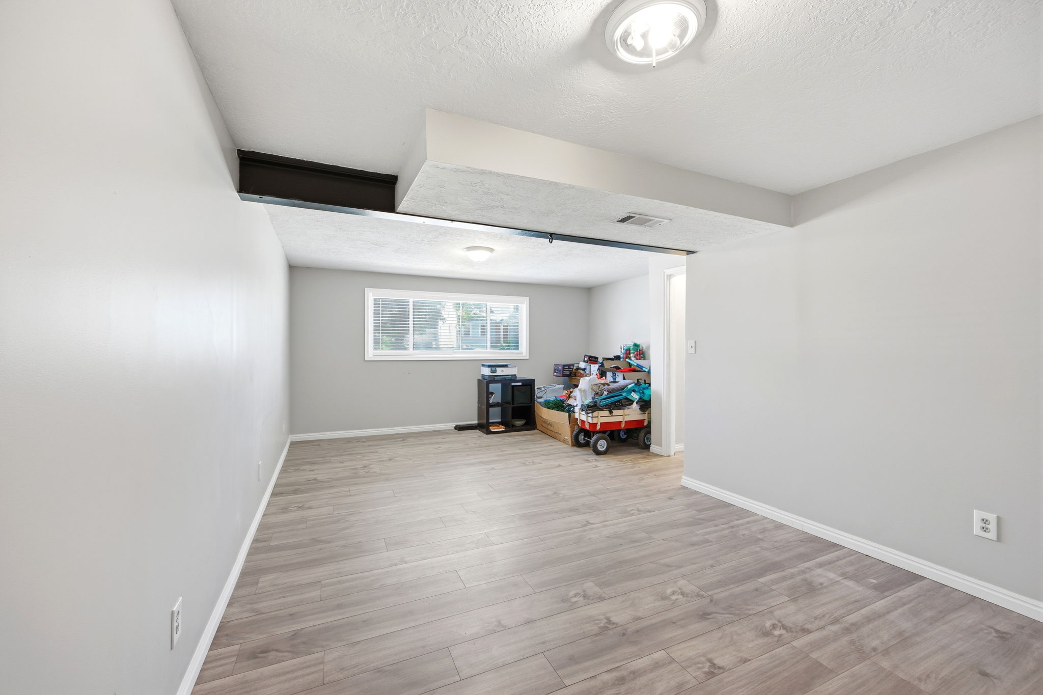Spacious room featuring wood-finish flooring and light gray walls