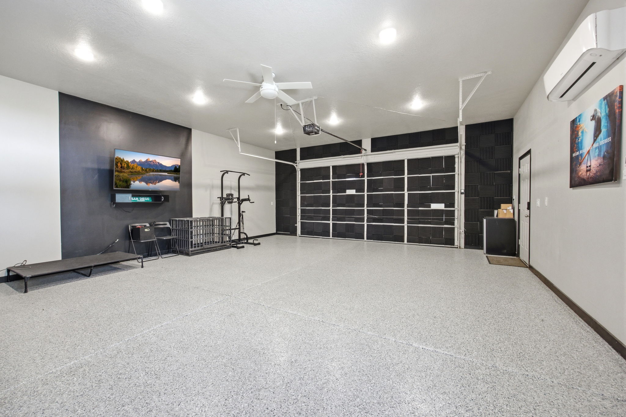 Spacious garage featuring a durable epoxy floor, overhead ceiling fan, recessed lighting, and a ductless mini-split system