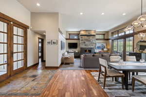 Open-concept living space featuring wood-finish flooring, a stone-clad fireplace, and expansive sliding glass doors