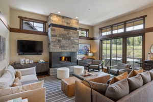 Living room featuring a stacked stone fireplace with a built-in firebox, wood-finish flooring, and expansive glass sliding doors