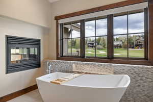 Freestanding soaking tub with a built-in fireplace, set against a mosaic tile backdrop