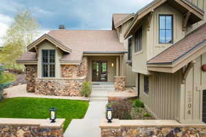 Stone and siding exterior featuring a prominent gabled entry with double doors