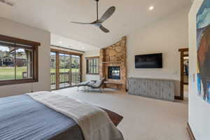 Vaulted ceiling bedroom with a stone-clad fireplace and integrated television