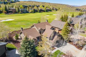 Expansive property featuring golf course frontage, multiple gabled roofs, a paved driveway, mature trees, and landscaped grounds