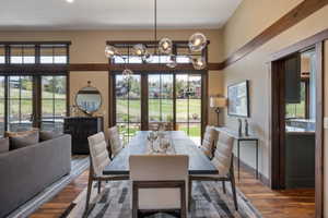 Dining area featuring wood-finish flooring, a contemporary chandelier, and a large area rug