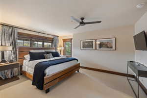 Carpeted bedroom featuring a wooden bed frame, built-in window with wooden trim, and a ceiling fan
