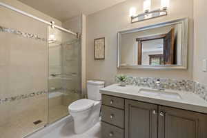 Bathroom featuring a vanity with an integrated sink, a mosaic tile backsplash, and a framed mirror