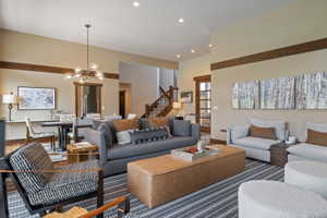Spacious living area featuring high ceilings, exposed wood beams, recessed lighting, and wood-finish flooring