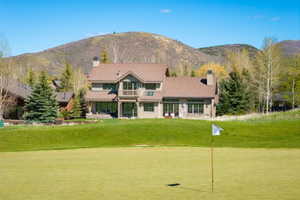 Golf course frontage featuring a two-story residence with a balcony, multiple patios, and a stone chimney