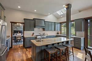 Spacious kitchen featuring an island with stone countertop, stainless steel appliances, recessed lighting, and skylights