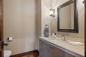 Vanity featuring a stone countertop with an integrated sink, brushed nickel faucet, and a large framed mirror