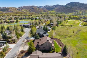 Mountain landscape featuring a residential area with mature trees, paved streets, and a prominent golf course with a pond