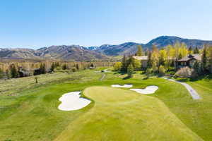 Expansive golf course green with sand traps, surrounded by lush landscaping and mature trees