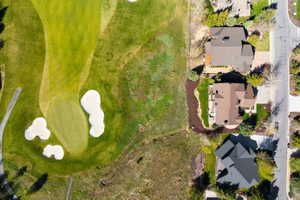 Aerial perspective showcasing a property bordering a golf course with a green and sand traps