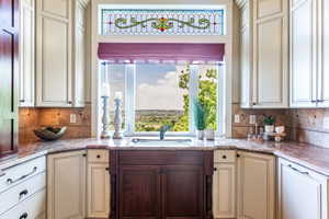 Kitchen window with a built-in sink featuring light-toned cabinetry, a contrasting dark wood base cabinet, and granite countertops