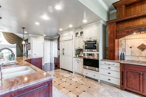 Gourmet kitchen featuring a built-in refrigerator, double ovens, and a large central island with an integrated sink